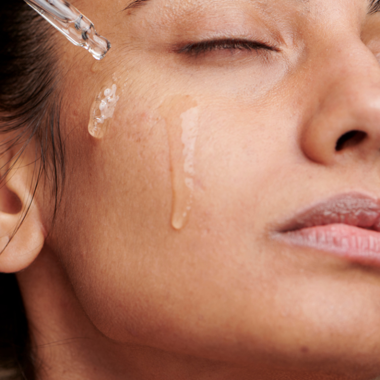 Vrouw druppelt Jojoba olie op het gezicht