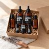 Baardolie-maakpakket in een kraft cadeaudoos met papiervulling: jojoba-olie, castorolie, vitamine E-olie, cederhout- en lavendelolie en twee lege druppelflesjes